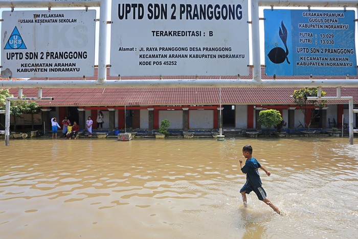 Seorang anak bermain air saat banjir menggenangi SDN 02 Pranggong, Kecamatan Arahan, Indramayu, Jawa Barat, Senin (18/7/2022). Pihak sekolah terpaksa meliburkan siswanya pada hari pertama masuk sekolah karena sejumlah ruang kelas terendam banjir akibat luapan sungai Cipelang. ANTARA FOTO/Dedhez Anggara/hp.