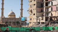 Pekerja Palestina membersihkan puing-puing bangunan yang hancur di kota Gaza, usai serangan udara Israel.