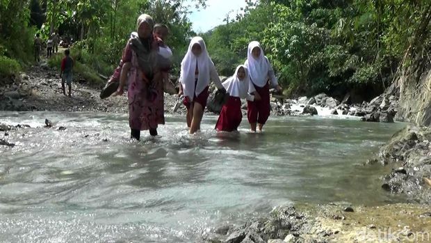 Sejumlah siswa didampingi orang tua menyeberangi sungai saat berangkat ke sekolah.