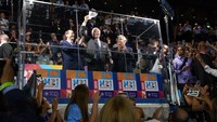 Presiden Joe Biden melambaikan topi saat ia berdiri di belakang partisi kaca dengan Presiden Israel Isaac Herzog, kiri, dan Perdana Menteri Israel Yair Lapid selama upacara pembukaan Maccabiah Games di Stadion Teddy di Yerusalem, Israel, Kamis (14/7/2022)waktu setempat. (AP Photo/Evan Vucci)  