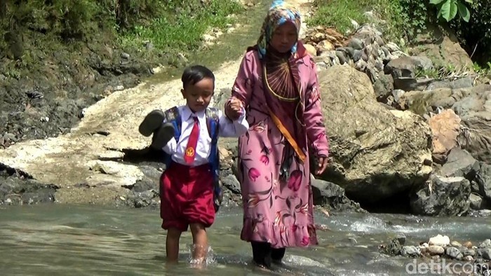 Warga dan anak sekolah saat menyebrangi Sungai Mondo di Kecamatan Pagedongan, Banjarnegara, Senin (18/7/2022).