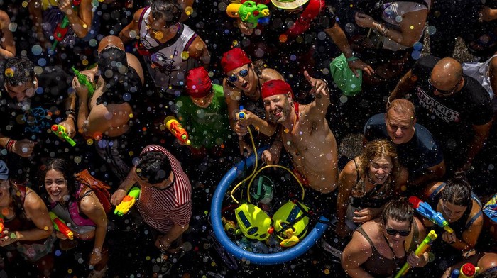 People throw water at each other during the annual water fight in the streets of the Vallecas neighborhood of Madrid, Spain, Sunday, July 17, 2022. (AP Photo/Manu Fernandez)
