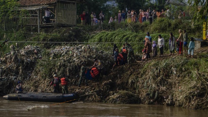Tim SAR gabungan membantu pelajar turun dari perahu karet setelah menyeberangi Sungai Cimanuk, Garut, Jawa Barat, Selasa (19/7/2022). Warga di kawasan tersebut terpaksa menggunakan perahu karet yang disediakan oleh Tim SAR gabungan Polri, TNI dan Badan Penanggulangan Bencana Daerah (BPBD) Garut untuk akses penyeberangan, khususnya untuk menuju sekolah setelah jembatan penghubung antarkecamatan dampak banjir bandang Sungai Cimanuk beberapa waktu lalu. ANTARA FOTO/Novrian Arbi/rwa.
