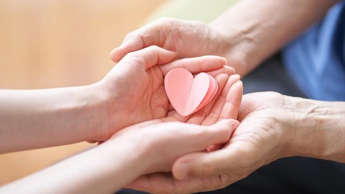Hands of caregivers and elderly people with heart-shaped objects