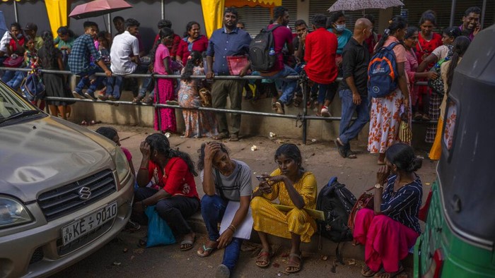 People wait in queue to get their passports outside Department of Immigration & Emigration in Colombo, Sri Lanka, Monday, July 18, 2022. The Indian Ocean island nation is engulfed in an unprecedented economic crisis that has triggered political uncertainty. (AP Photo/Rafiq Maqbool)