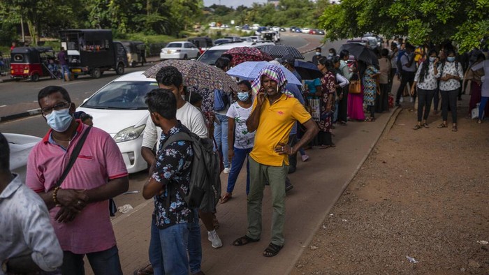 People wait in queue to get their passports outside Department of Immigration & Emigration in Colombo, Sri Lanka, Monday, July 18, 2022. The Indian Ocean island nation is engulfed in an unprecedented economic crisis that has triggered political uncertainty. (AP Photo/Rafiq Maqbool)