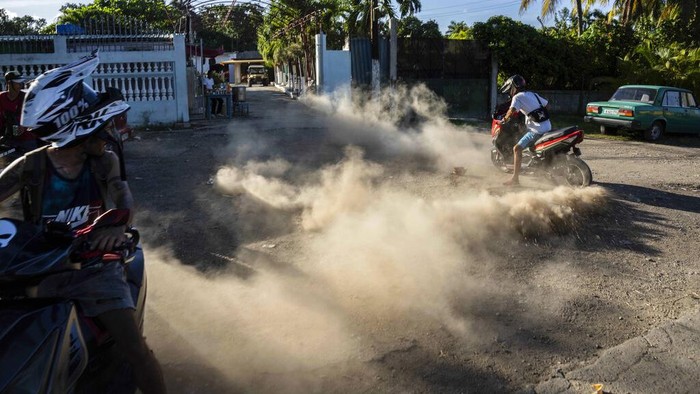 A biker kicks up dust at a late afternoon gathering by electric scooterists to show off stunts and race in Havana, Cuba, Friday, July 15, 2022. Cuba has been flooded in recent years with “motorinas”, as these electric scooters are called on the island, a fad for many, but also a solution to the transportation problems and fuel shortages that overwhelm the Caribbean nation. (AP Photo/Ramon Espinosa)