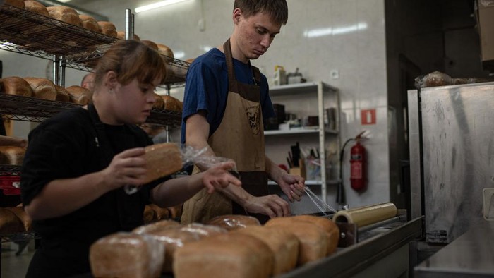 KYIV, UKRAINE - JULY 19: Good Bread bakery worker takes loafs of bread from the oven on July 19, 2022 in Kyiv, Ukraine. Good Bread bakery has been employing people with mental disabilities since its opening several years ago. Weeks after the Russian invasion, the bakery returned to work to bake bread for thousands of people in need. Now the bakery distributes nearly a 1000 loaves of bread per day for soldiers of the Armed Forces and Territorial Defense, the police, hospital patients, residents of mental hospitals, elderly people, and families with children who stayed in Kyiv, as well as the residents of the villages and towns that were destroyed during the Russian invasion. (Photo by Alexey Furman/Getty Images)