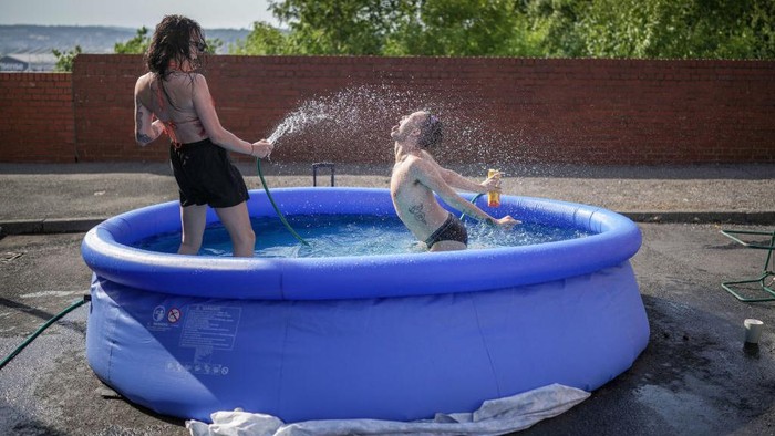 1409737630 LEEDS, UNITED KINGDOM - JULY 19: A family enjoy a barbecue and cool off in apaddling pool outside their home on July 19, 2022 in Leeds, United Kingdom. Temperatures exceeded 40C in parts of England today after the Met Office issued its first red extreme heat warning. Record-breaking temperatures were reached across the UK. (Photo by Christopher Furlong/Getty Images)
