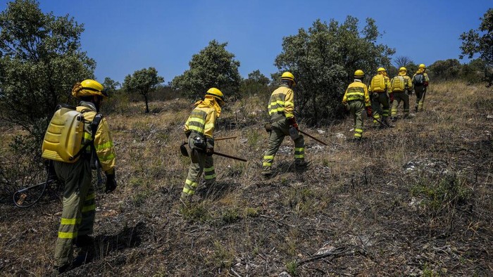 Firefighters work at the scene of a wildfire in Tabara, Spain, Tuesday, July 19, 2022. Firefighters battled wildfires raging out of control in Spain and France as Europe wilted under an unusually extreme heat wave that authorities in Madrid blamed for hundreds of deaths. (AP Photo/Bernat Armangue)