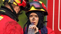 Petugas pemadam kebakaran beristirahat setelah memadamkan kebakaran hutan yang berkobar lagi di desa Lagoa Parada, dekat Ansiao tengah Portugal, 14 Juli 2022. Ribuan petugas pemadam kebakaran di Portugal telah memadamkan api di seluruh negeri yang memaksa evakuasi puluhan orang. (AP/Armando Franca)