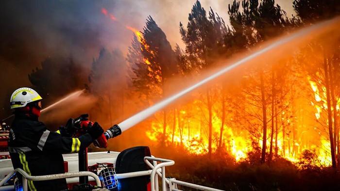 This photo provided Friday July 15, 2022 by the fire brigade of the Gironde region (SDIS 33) shows firefighters using hose to fight a wildfire near Landiras, southwestern France, Thursday, July 14, 2022. Several hundred firefighters struggled Friday to contain two wildfires in the Bordeaux region of southwest France that have forced the evacuation of 10,000 people and ravaged more than 7,000 hectares of land. High temperatures and strong winds have complicated firefighting efforts in the region, one of several around Europe scorched by wildfires this season. (SDIS 33 via AP)