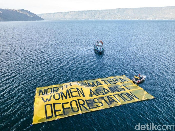 Aktivis Greenpeace membentangkan spanduk raksasa di Danau Toba.