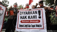 Dengan memakai ikat kepala merah putih, mereka terus berorasi di depan kantor BUMN.