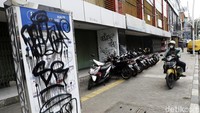 Papan informasi rute itu dicoret-coret dengan tulisan aneka warna.