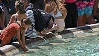 Turis-turis ini menyegarkan diri dengan air dari Trevi Fountain, di Roma, di tengah gelombang panas yang melanda Eropa. (Getty Images)