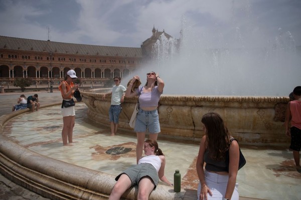 Setelah jalann-jalan, orang-orang mendinginkan diri dengan air mancur selama gelombang panas di Seville. (Getty Images)