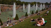 Bertepatan dengan liburan musim panas, warga dan turisnya mampir ke Menara Eiffel. Saking panasnya, mereka merendam kaki, kepala bahkan badan di kolam air mancur.  (AFP via Getty Images)