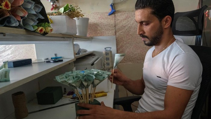 Mohamad Farah works on preparing a bouquet made out of Lebanese pound banknotes at a shop in a suburb of Beirut, Lebanon July 13, 2022. REUTERS/Emilie Madi