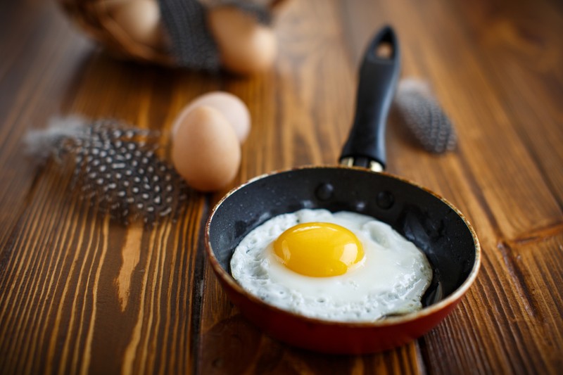 fried eggs in a frying pan on a table with eggs guinea fowl