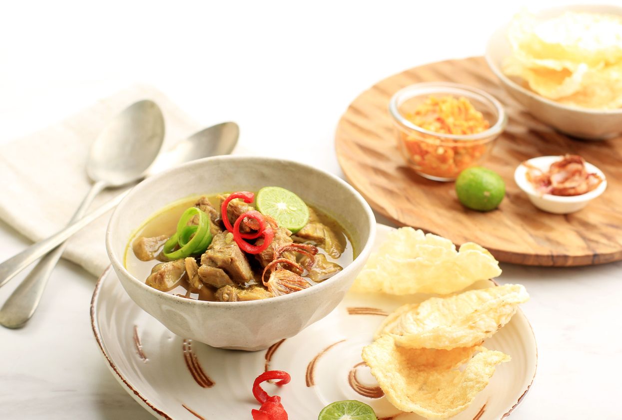 Soto Daging Indonesian Beef Soup, Served on Ceramic bowl with Krupuk Melinjo, Sambal, and Lime