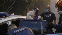 Petugas polisi dan petugas pemadam kebakaran membawa warga lanjut usia keluar dari rumah mereka ke tempat yang aman.