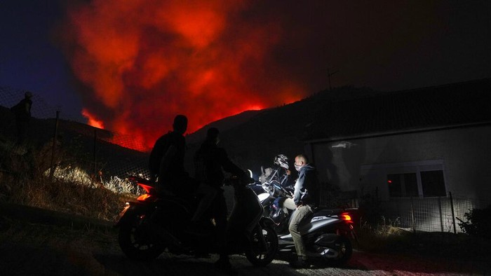 Kebakaran Hutan di Yunani Paksa Ratusan Orang Mengungsi A firefighter pulls a hose as the fire burns near a house at Mount Penteli, northeast of Athens, Tuesday, July 19, 2022. Fire Service officials said nine firefighting aircraft and four helicopters were deployed to try and stop the flames reaching inhabited areas on the slopes of Mount Penteli, some 25 kilometers (16 miles) northeast of the Athens. (AP Photo/Thanassis Stavrakis)