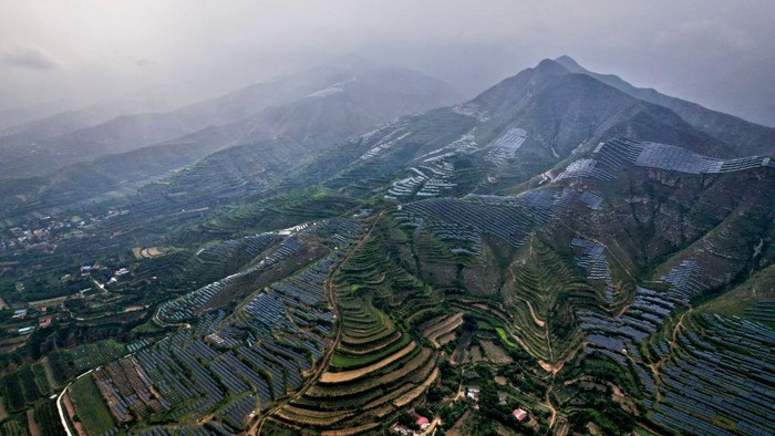 Ladang Panel Surya 'Selimuti' Pegunungan di China YUNCHENG, CHINA - JULY 16, 2022 - Aerial photo taken on July 16, 2022 shows the Rain-washed Ruicheng Photovoltaic base in Yuncheng city, Shanxi Province, China. Located at the southern foot of Zhongtiao Mountain, Ruicheng Photovoltaic Leading technology Base, with a total investment of 8.8 billion yuan, stretches 80 kilometers and involves 8 towns and villages in the whole county. It is the first approved county-level photovoltaic leading technology base project in China. (Photo credit should read CFOTO/Future Publishing via Getty Images)