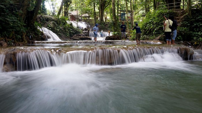 Wisatawan mengunjungi objek wisata Air Terjun Pilaweanto di Desa Salodik, Kabupaten Banggai, Sulawesi Tengah, Rabu (20/7/2022). Objek wisata alam tersebut memiliki air terjun yang bersusun dengan air biru yang jernih, kanopi hutan dan pemandangan alam yang indah. ANTARA FOTO/Adiwinata Solihin/rwa.