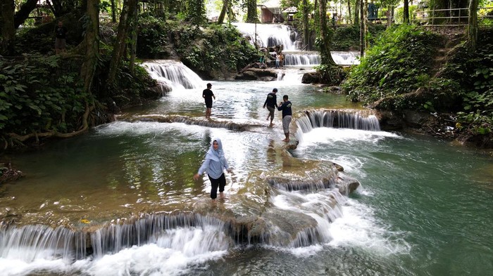 Wisatawan mengunjungi objek wisata Air Terjun Pilaweanto di Desa Salodik, Kabupaten Banggai, Sulawesi Tengah, Rabu (20/7/2022). Objek wisata alam tersebut memiliki air terjun yang bersusun dengan air biru yang jernih, kanopi hutan dan pemandangan alam yang indah. ANTARA FOTO/Adiwinata Solihin/rwa.