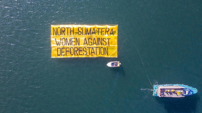 Sebuah spanduk raksasa bertuliskan 'Perempuan Sumatera Utara Menolak Deforestasi' mengapung di kawasan Danau Toba.