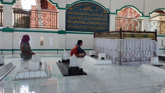 Sepasang peziarah tengah berdoa di depan makam Sunan Pojok, Minggu (17/7/2022)