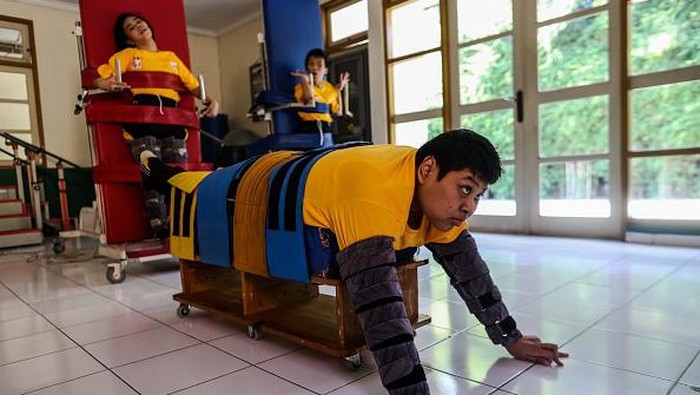 Terapi Untuk Anak-anak Selebral Palsi di Wisma Palsigunung JAKARTA, INDONESIA - JULY 8: Children with cerebral palsy react while standing during a training session at the Wisma Tuna Ganda Palsigunung rehabilitation center in Jakarta, Indonesia on July 8, 2022. Palsigunung homestay, founded in 1975 by Sophie Sarwono, can house about 30 patients. It treats children with cerebral palsy, a physical and mental disability, by providing them with sensory-motor therapy, and physical and speech training five days a week. Physical training is important as patients have limited body movements, and it could be fatal if they were to remain inactive. (Photo by Garry Lotulung/Anadolu Agency via Getty Images)