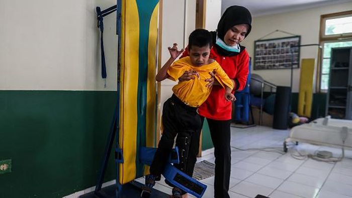 JAKARTA, INDONESIA - JULY 8: Children with cerebral palsy react while standing during a training session at the Wisma Tuna Ganda Palsigunung rehabilitation center in Jakarta, Indonesia on July 8, 2022. Palsigunung homestay, founded in 1975 by Sophie Sarwono, can house about 30 patients. It treats children with cerebral palsy, a physical and mental disability, by providing them with sensory-motor therapy, and physical and speech training five days a week. Physical training is important as patients have limited body movements, and it could be fatal if they were to remain inactive. (Photo by Garry Lotulung/Anadolu Agency via Getty Images)