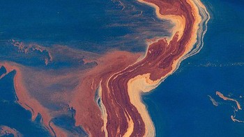 Foto drone memperlihatkan tumpahan minyak berwarna coklat kekuningan berpadu dengan biru laut.