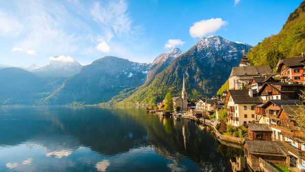 Scenic nature landscape view of Hallstatt mountain village reflecting in Hallstatter see lake against The Austrian Alpines in with morning sunshine and beautiful blue cloudy sky looking like a postcard picture in Salzkammergut region, Austria xxxl size april 2017