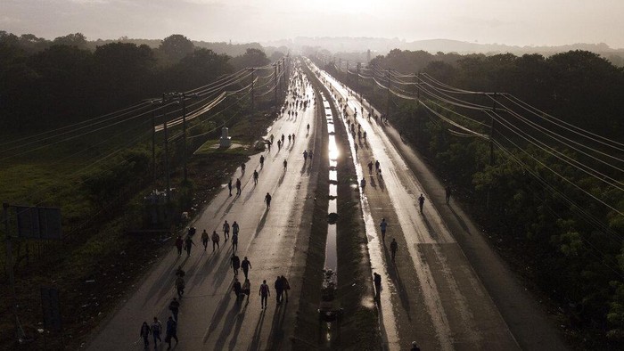 Commuters walk along the Pan American Highway due to roadblocks set up by protesters demonstrating against inflation, especially surging fuel prices, in Pacora, Panama, early Wednesday, July 20, 2022. (AP Photo/Arnulfo Franco)