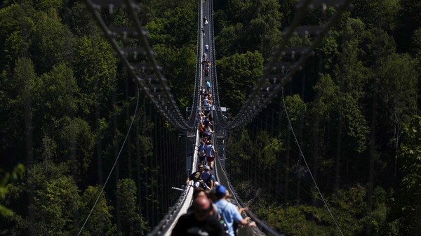 Pengunjung menyeberangi jembatan gantung di Hasselfelde, Jerman, Selasa (19/7/2022) waktu setempat.  