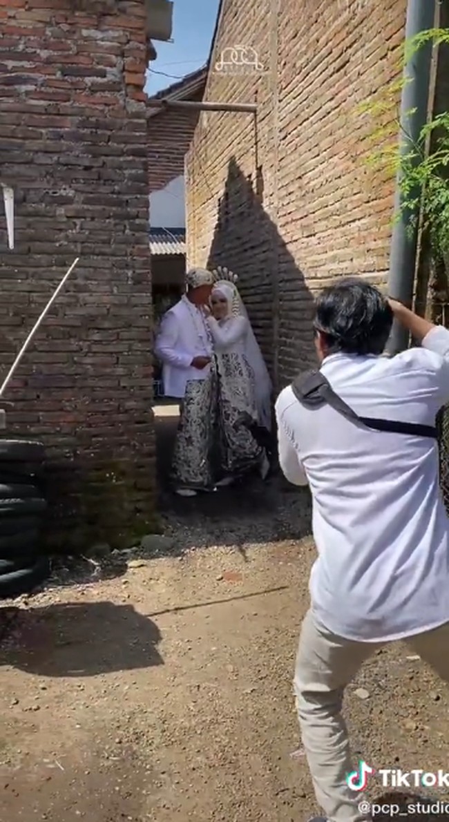 Pasangan pengantin ini mengadakan sesi foto post wedding di tempat tak biasa. Fotografer mengabadikan momen foto pengantin di dekat kompor dan gang di dekat rumah pengantin. Hasil foto bikin warganet kagum.  Foto: Dok. TikTok @pcp_studio.