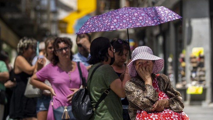 A woman queues to buy tickets of lottery during a hot and sunny day in Madrid, Spain, Monday, July 18, 2022. (AP Photo/Manu Fernandez)