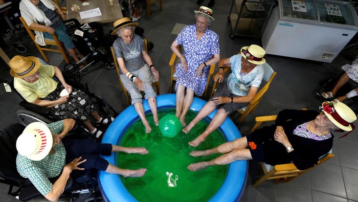 Begini Cara Para Lansia di Belgia Hadapi Gelombang Panas Residents at the Ter Biest house for elderly persons Rachel De Smedt, 89, Marie-Louise Buggenhout, 90, Mariette Van Dam, 90, Lisette Donies, 88 and Irma Van Buggenhout, 93, dip their feet in a pool as a heat wave hits Europe, in Grimbergen, Belgium July 19, 2022. REUTERS/Yves Herman