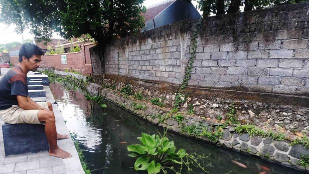 Komang Sudantra (40) tampak bersantai sembari menikmati suasana di sungai Grodogan pada Jumat (22/7/2022)