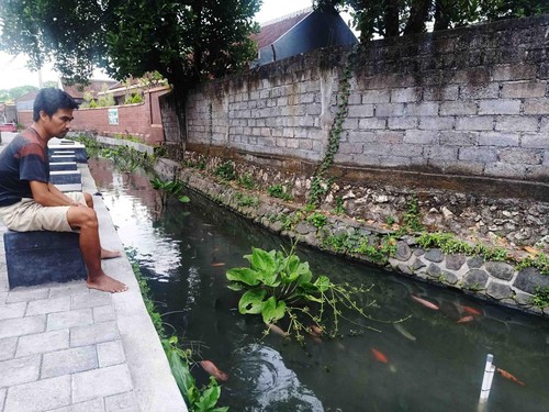 Komang Sudantra (40) tampak bersantai sembari menikmati suasana di sungai Grodogan pada Jumat (22/7/2022)