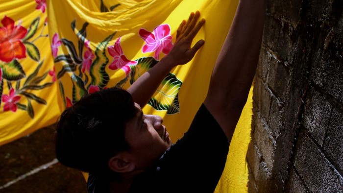 A worker drying the beach sarongs  at the home industry of beach sarongs in Seneporejo village, East Java Province, Indonesia, on July 20, 2022. These home-made industrial beach sarongs are marketed to major cities in Indonesia and also marketed to Thailand, New Zealand, India and Japan. The production of beach sarongs reaches 500 pieces per day by employing young people who drop out of school and is sold for IDR 80,000 per piece.
 (Photo by Aman Rochman/NurPhoto via Getty Images)