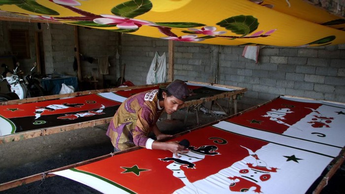 A worker drying the beach sarongs  at the home industry of beach sarongs in Seneporejo village, East Java Province, Indonesia, on July 20, 2022. These home-made industrial beach sarongs are marketed to major cities in Indonesia and also marketed to Thailand, New Zealand, India and Japan. The production of beach sarongs reaches 500 pieces per day by employing young people who drop out of school and is sold for IDR 80,000 per piece.
 (Photo by Aman Rochman/NurPhoto via Getty Images)
