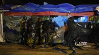 Sejumlah tentara dengan perlengkapan antihuru-hara berbaris di area penggerebekan. 