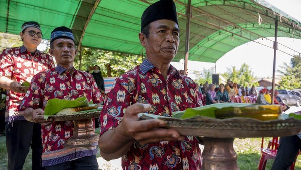 Warga menyajikan makanan kepada tetua adat untuk disantap bersama pada acara Povunja atau syukuran setelah selesai masa panen di Sigi, Sulawesi Tengah (Sulteng), Kamis (21/7/2022).   
