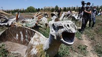 Dari luar, terdapat mainan dinosaurus yang tak terurus dikelilingi rumput liar. Suasana taman sunyi. Mainan rusak dan cuma jadi sarang debu. 