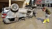 Seorang fotografer terlihat mengabadikan momen sebuh mobil yang terbalik imbas hantaman banjir di Turki.