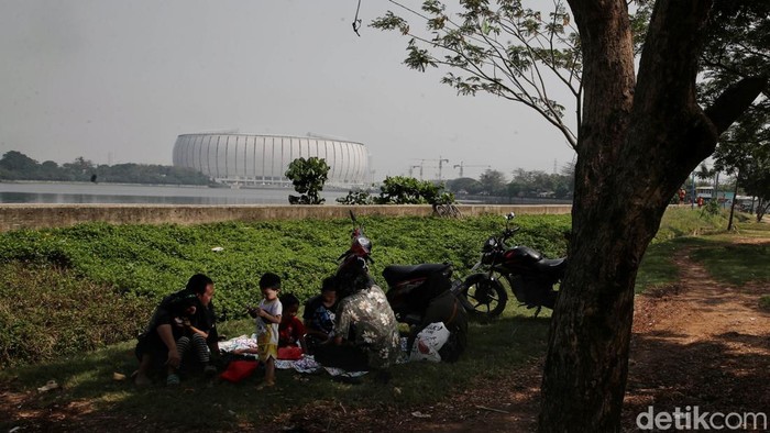 Sejumlah warga beraktivitas di kawasan Waduk Cincin dengan latar belakang Jakarta International Stadium (JIS),  Papanggo, Jakarta Utara, Kamis (21/7).